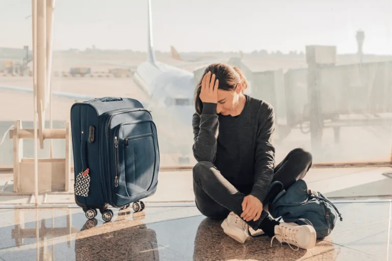 Woman with head in hands, cancelled flight representing change fatigue and disruption in implementation management.